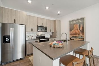 A kitchen with stainless steel appliances and a large island with bar stools